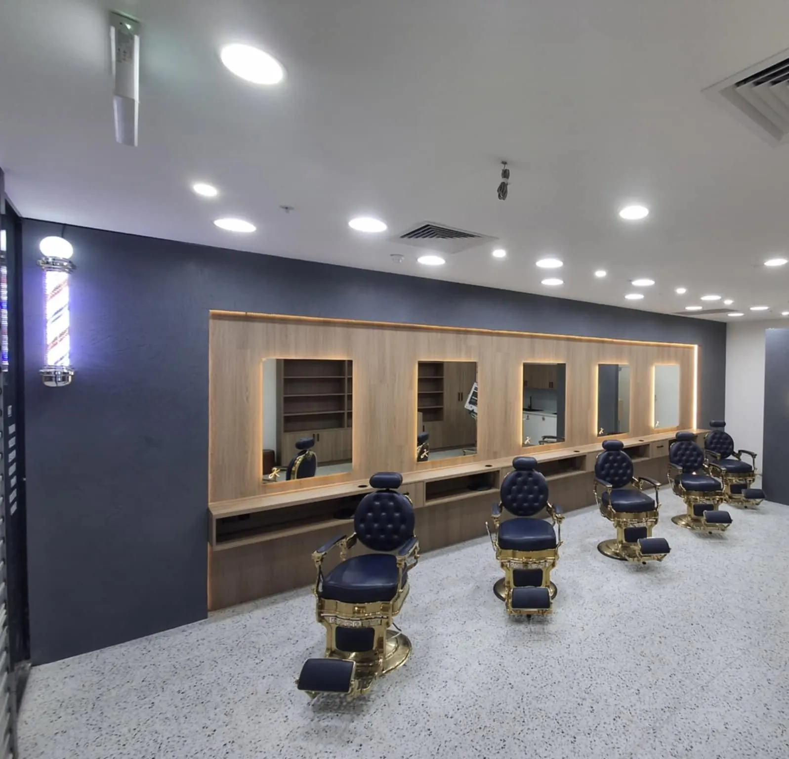 Barber stations along a timber-lined wall over a white terrazzo-look floor
