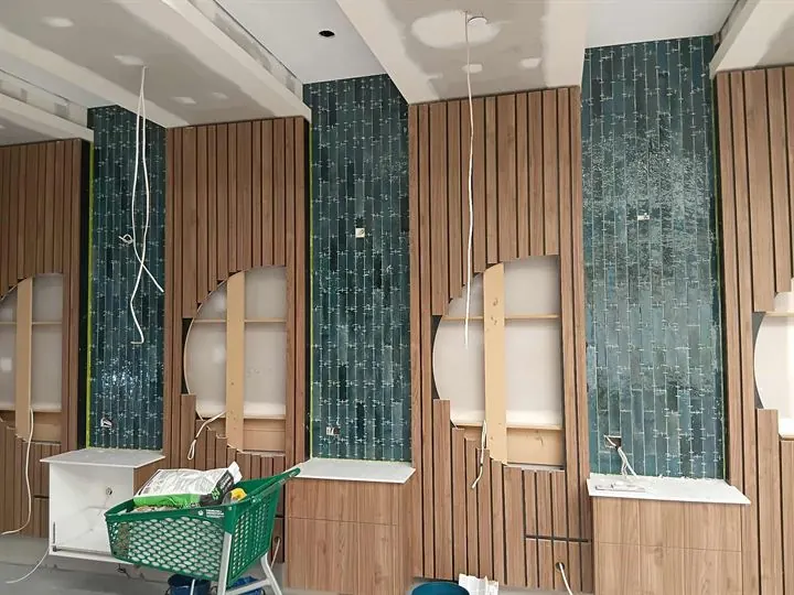 Green gloss mosaic tiles on columns between timber batten walls