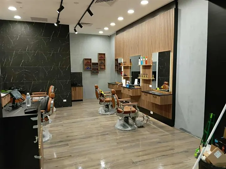 Barber shop with a dark marble-look feature wall and timber-look floor