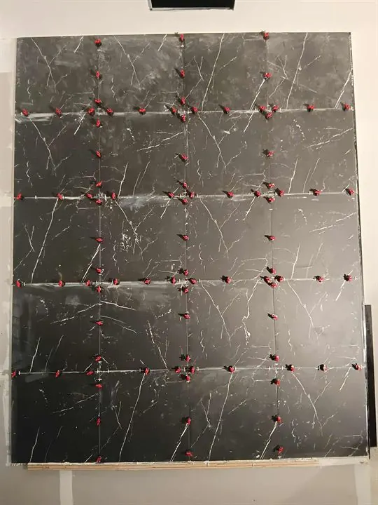 Large dark marble-look wall tiles going up with levelling clips on every joint