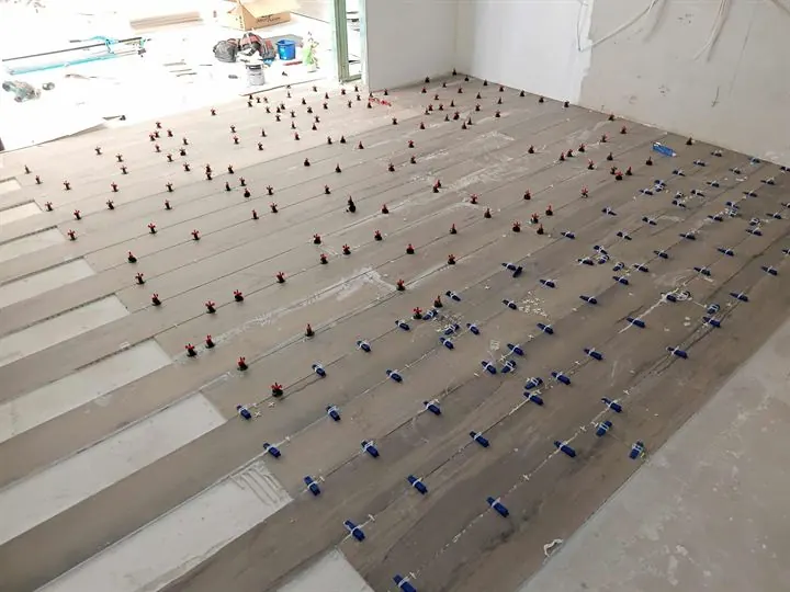 Timber-look plank tiles laid across a shop floor with levelling clips on every joint