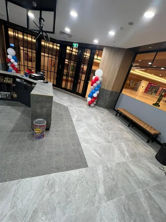 Shop entry with large grey floor tiles and a dark tiled inset leading in from the door