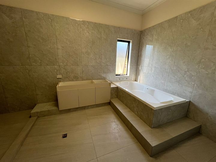 Bath and vanity set on tiled steps in a grey bathroom