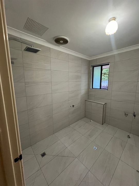 Bathroom tiled in light grey stone-look tiles, before fit-off