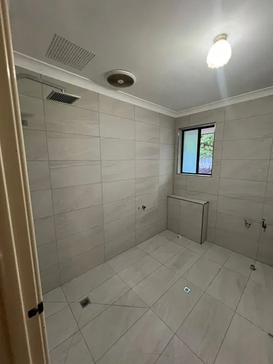 Bathroom retiled in light grey stone-look tiles