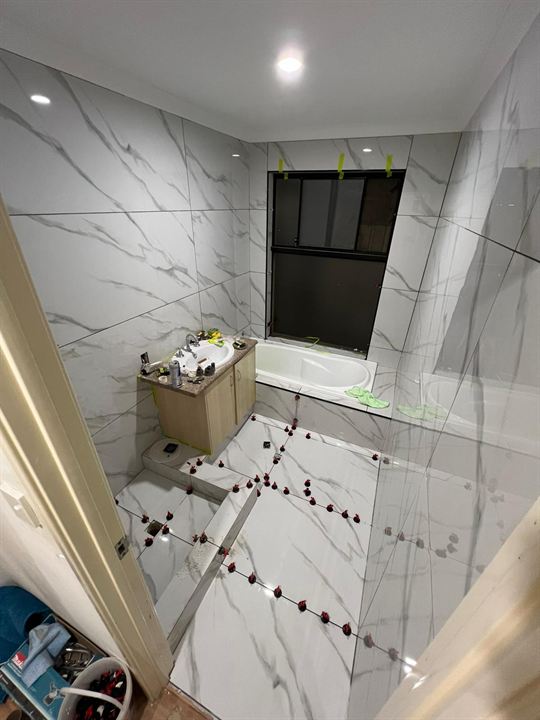 Levelling clips on a large-format bathroom floor during laying