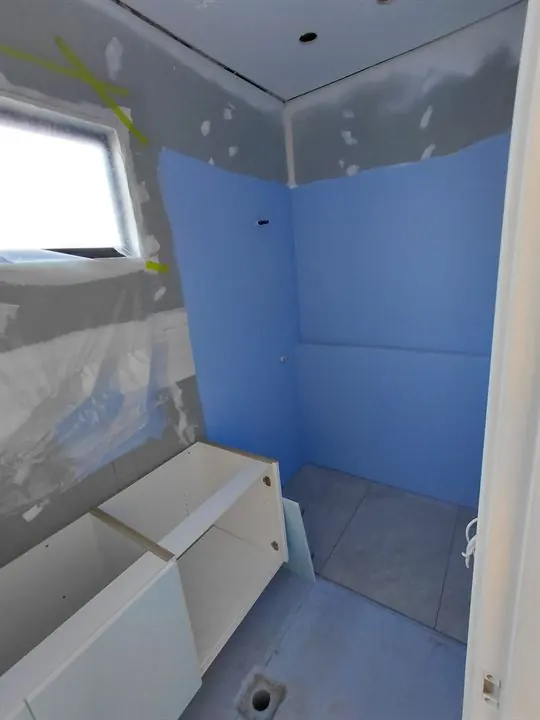 Shower walls and floor coated in blue waterproofing membrane