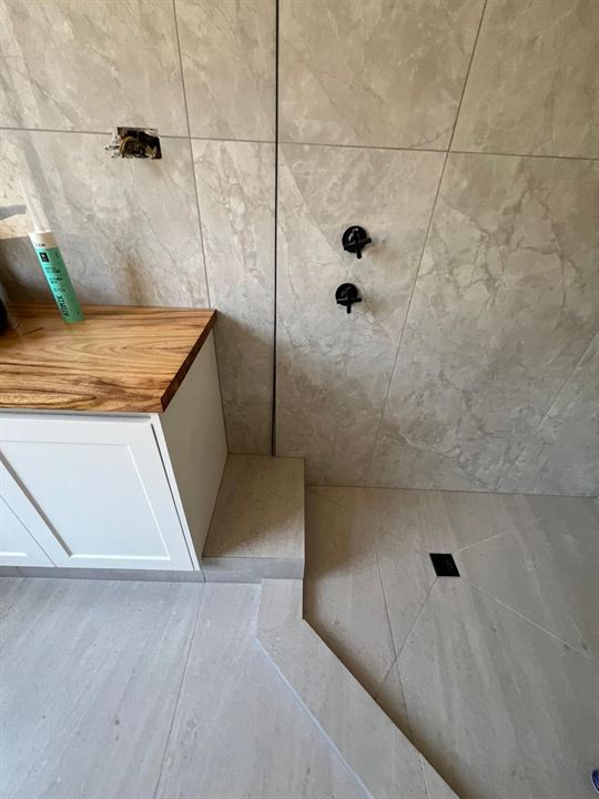Step-down shower floor beside a vanity with a timber top