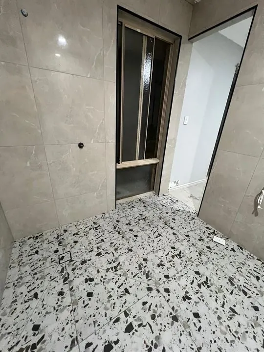Terrazzo-look bathroom floor with stone-look walls