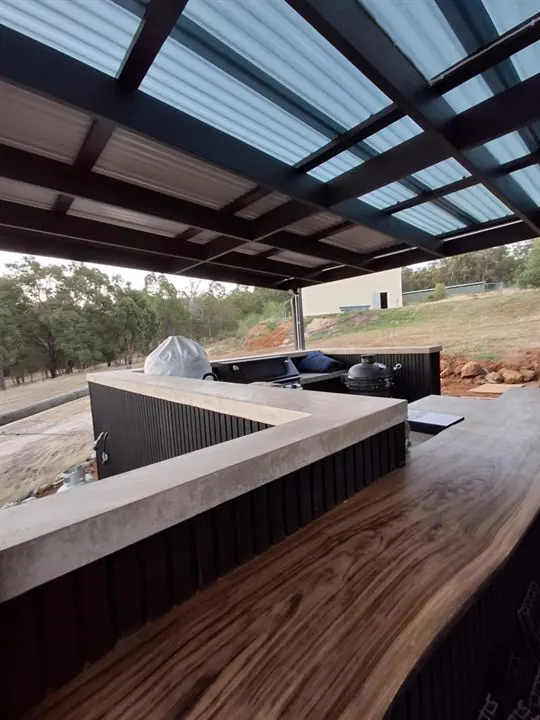 The outdoor bar finished, with a live-edge timber top and dark vertical cladding