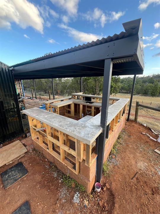 Timber-framed outdoor bar under a patio roof, with benchtops in place