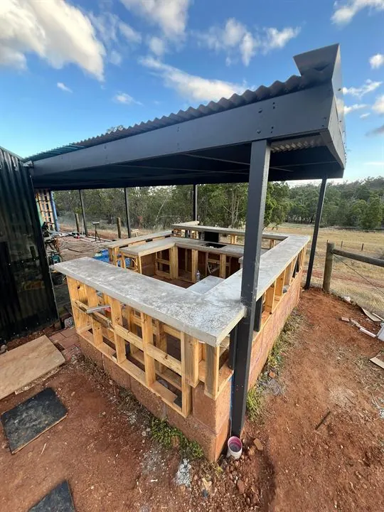 Timber-framed outdoor bar under a pergola, benchtops going on