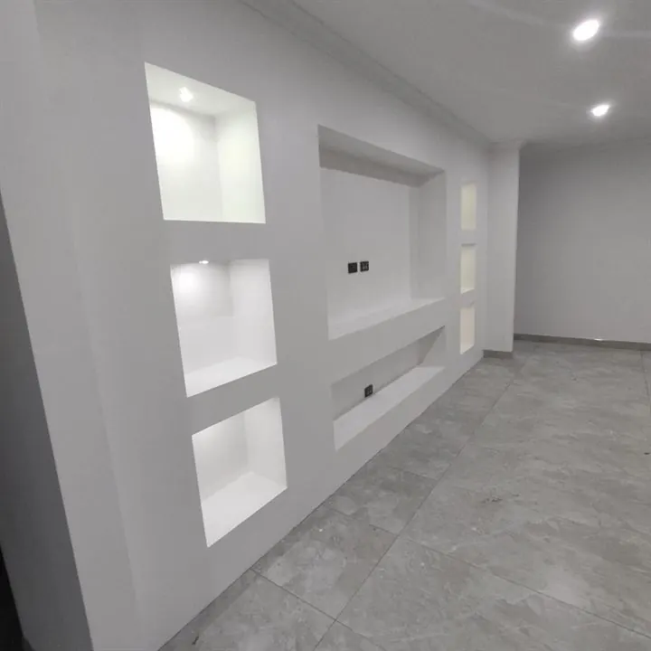 Living room wall with plasterboard niches lit by LED strips