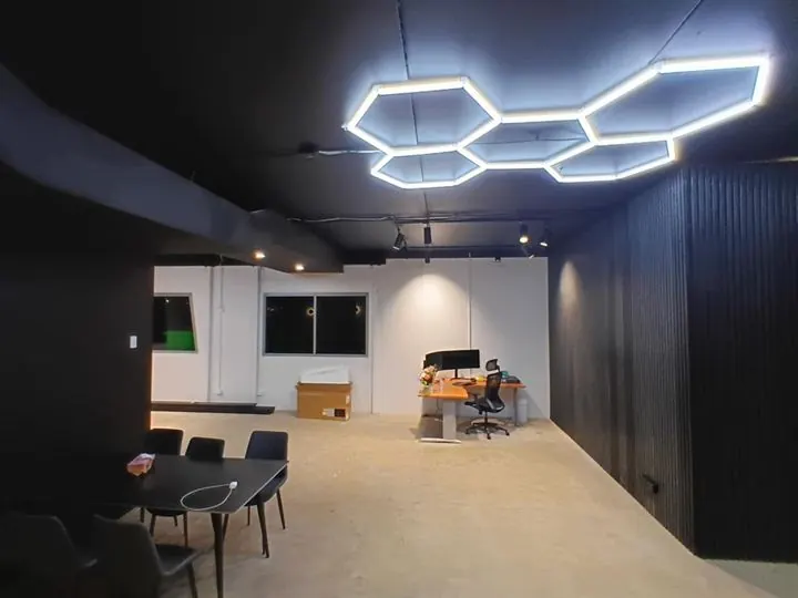 Office fit-out with black batten walls, a dark ceiling and hexagon lights