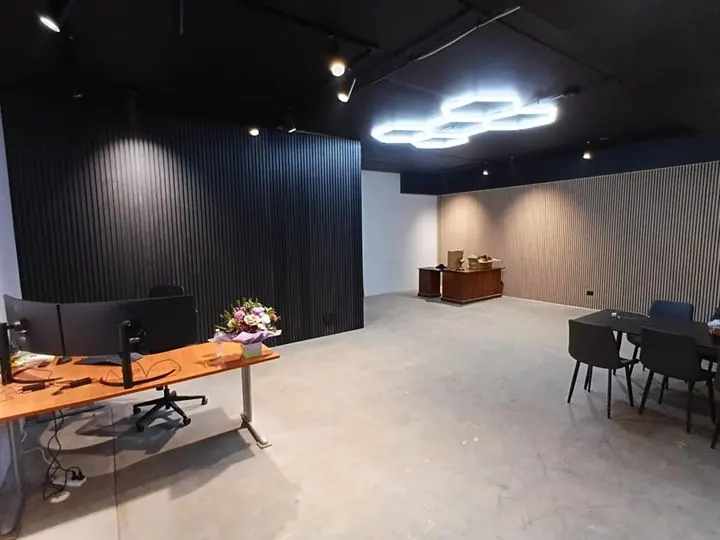 Open office with black batten walls, desks and a meeting table