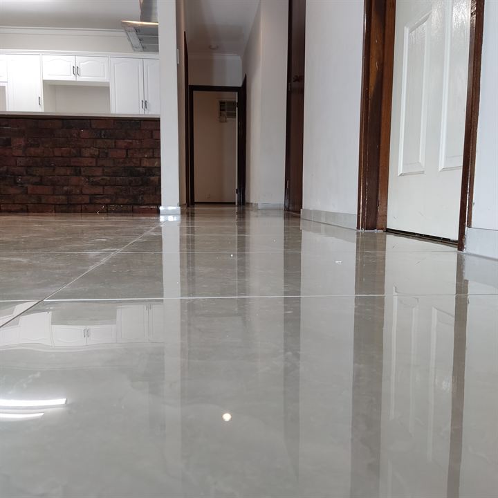 Glossy light grey floor tiles running through a living area to the hallway