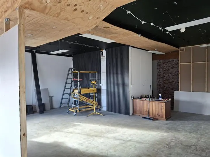 The bulkhead sheeted in plywood overhead, with black batten cladding going onto a feature wall behind