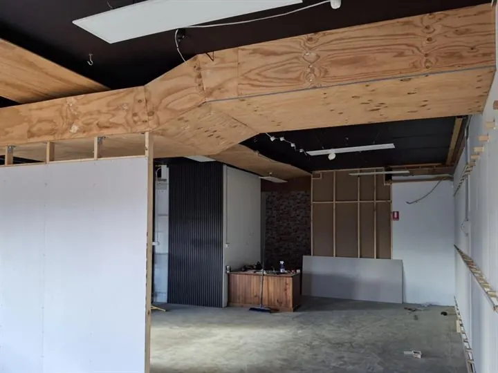 Office unit with a bulkhead sheeted in plywood across the ceiling and a new stud wall lined in plasterboard