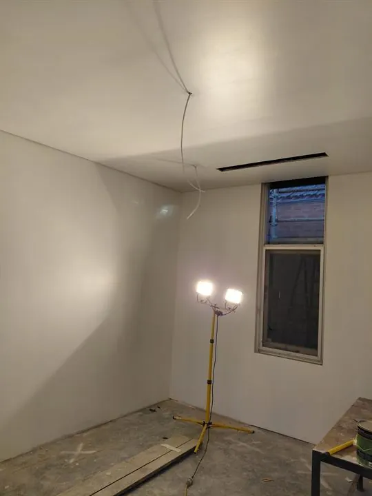 Bedroom with walls and ceiling sheeted and flushed, ready for paint