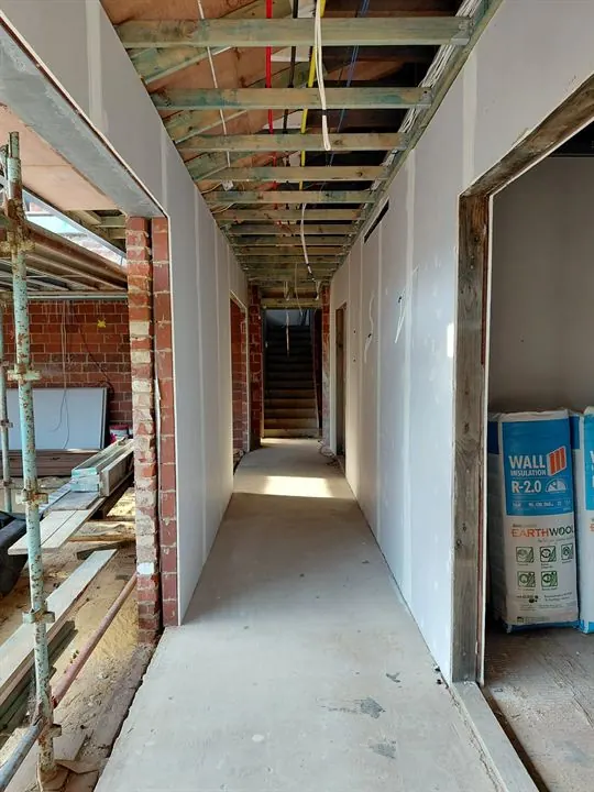 Long hallway with new plasterboard walls, ceiling battens still open above